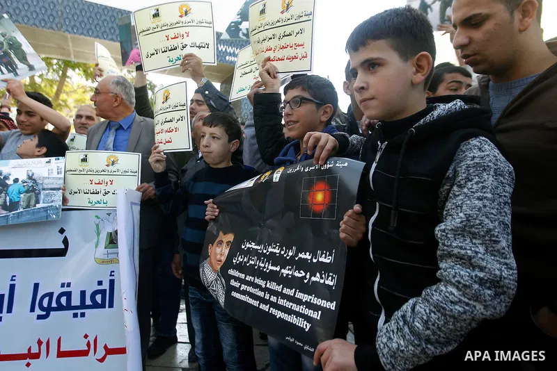 Palestinians hold banners during a protest to show solidarity with children prisoners in Israeli jails, in the West Bank city of Hebron, on November 21, 2016. Photo by Wisam Hashlamoun