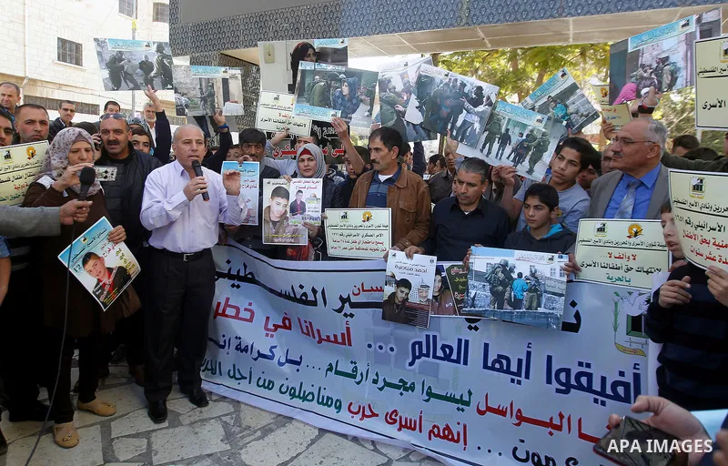 Palestinians hold banners during a protest to show solidarity with children prisoners in Israeli jails, in the West Bank city of Hebron, on November 21, 2016. Photo by Wisam Hashlamoun