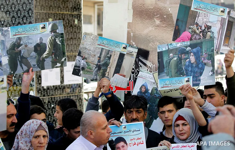 Palestinians hold banners during a protest to show solidarity with children prisoners in Israeli jails, in the West Bank city of Hebron, on November 21, 2016. Photo by Wisam Hashlamoun