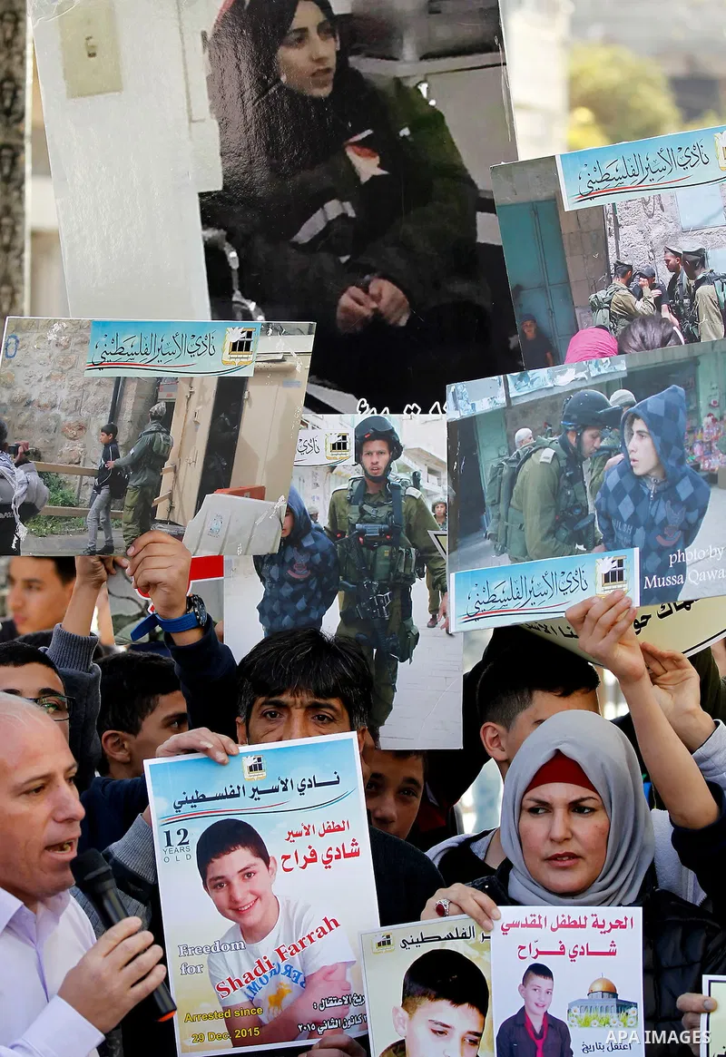 Palestinians hold banners during a protest to show solidarity with children prisoners in Israeli jails, in the West Bank city of Hebron, on November 21, 2016. Photo by Wisam Hashlamoun