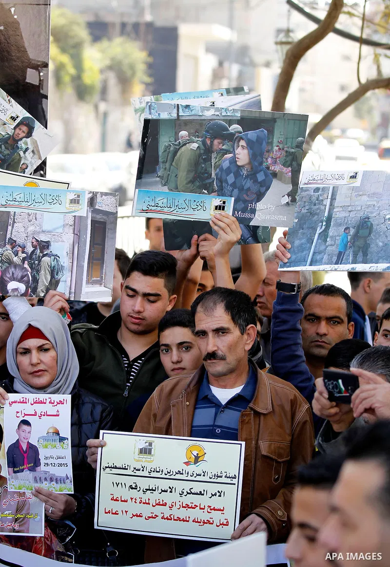Palestinians hold banners during a protest to show solidarity with children prisoners in Israeli jails, in the West Bank city of Hebron, on November 21, 2016. Photo by Wisam Hashlamoun