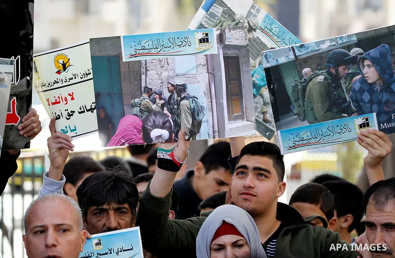 Palestinians hold banners during a protest to show solidarity with children prisoners in Israeli jails, in the West Bank city of Hebron, on November 21, 2016. Photo by Wisam Hashlamoun