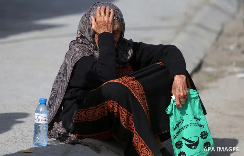 A Palestinian woman sits near the site where a Palestinian was shot dead after allegedly walking towards guards wielding a knife at the Qalandia checkpoint crossing between the West Bank city of Ramallah and Israeli-anne...