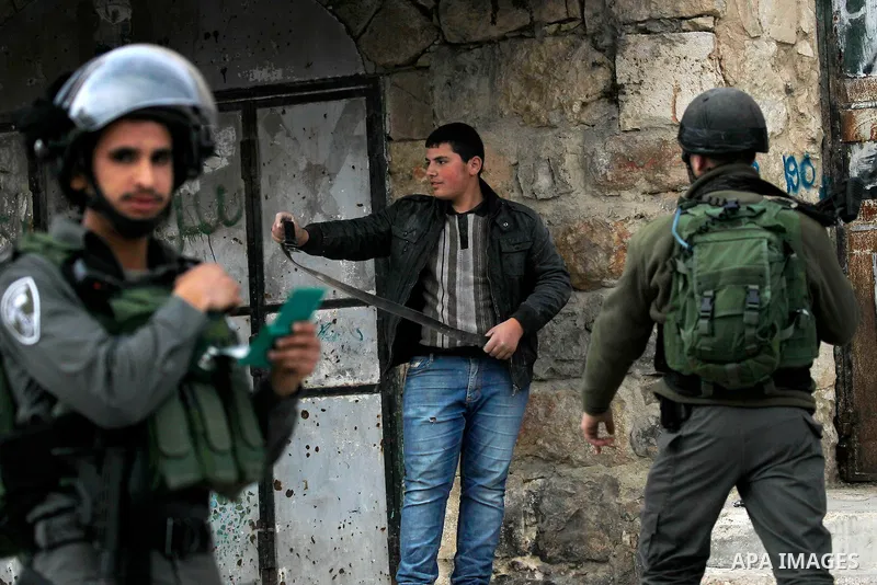 An Israeli soldier checks a Palestinian man at a checkpoint in the West Bank city of Hebron, on Nov. 22, 2016. Photo by Wisam Hashlamoun