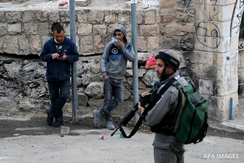 An Israeli soldier checks a Palestinian man at a checkpoint in the West Bank city of Hebron, on Nov. 22, 2016. Photo by Wisam Hashlamoun
