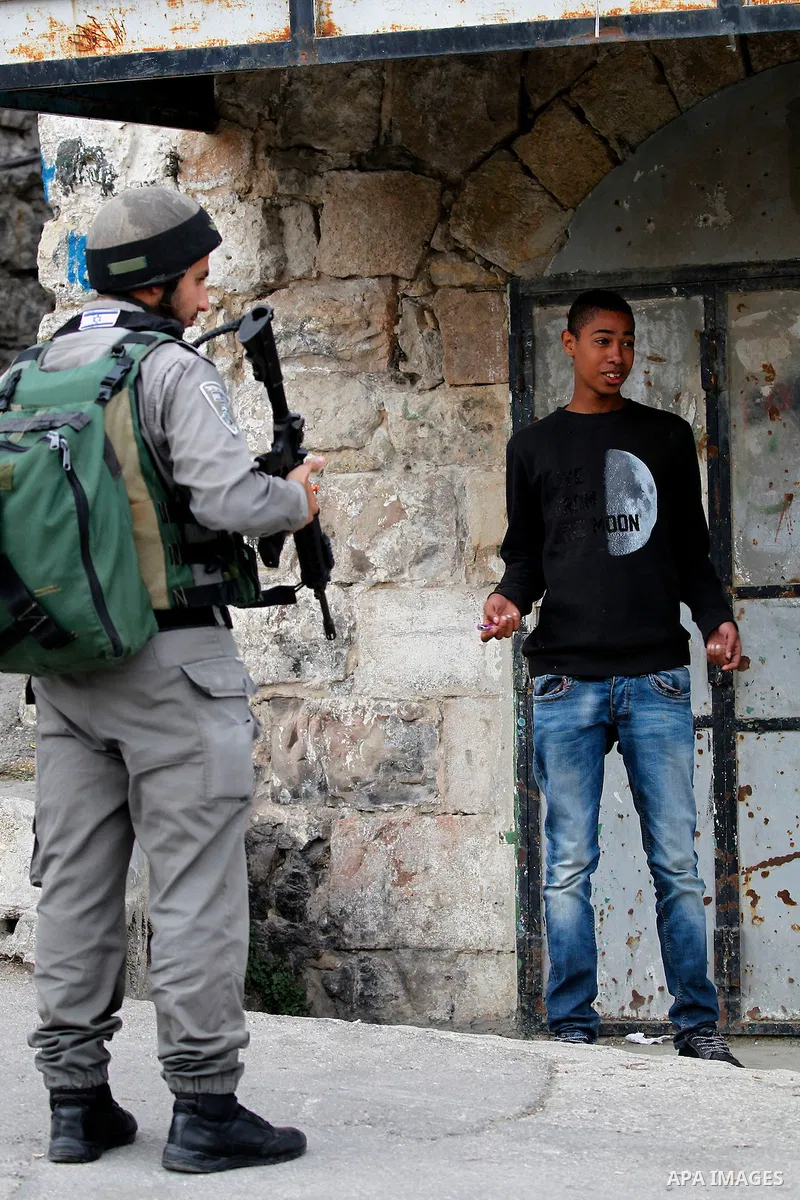 An Israeli soldier checks a Palestinian man at a checkpoint in the West Bank city of Hebron, on Nov. 22, 2016. Photo by Wisam Hashlamoun