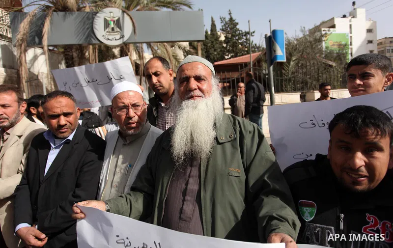 Palestinian workers hold banners during a protest demanding their rights in front of the Council of ministers headquarter, in Gaza city on November 24, 2016. Photo by Ashraf Amra