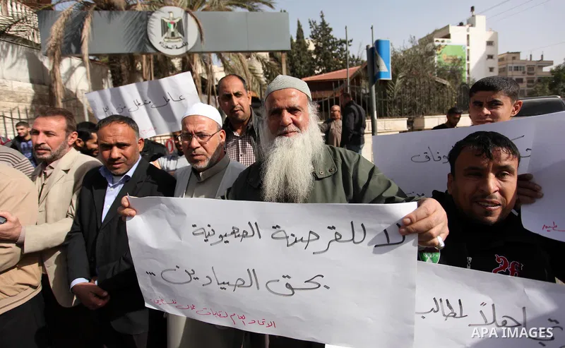 Palestinian workers hold banners during a protest demanding their rights in front of the Council of ministers headquarter, in Gaza city on November 24, 2016. Photo by Ashraf Amra