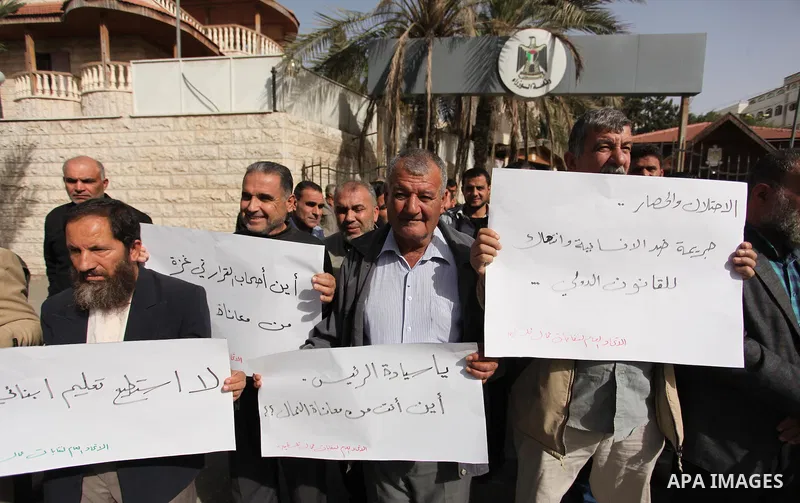 Palestinian workers hold banners during a protest demanding their rights in front of the Council of ministers headquarter, in Gaza city on November 24, 2016. Photo by Ashraf Amra