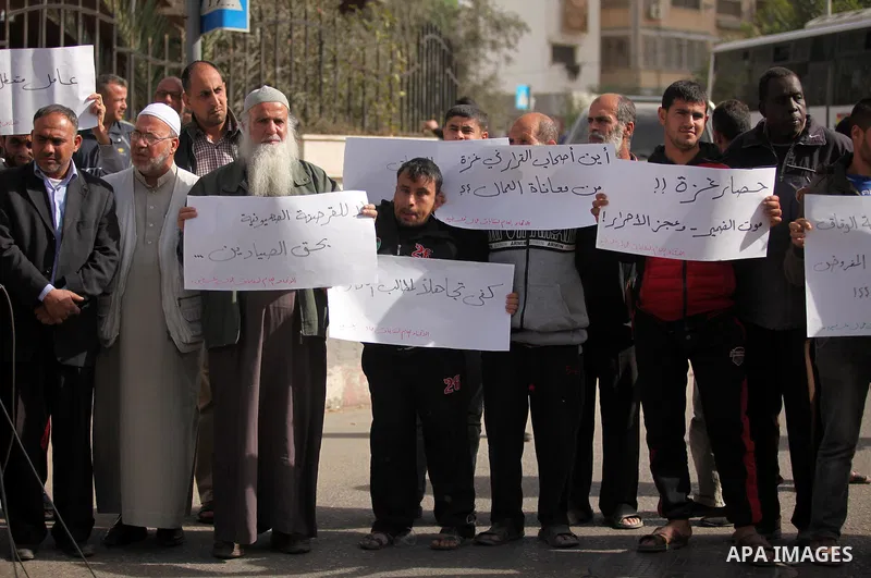 Palestinian workers hold banners during a protest demanding their rights in front of the Council of ministers headquarter, in Gaza city on November 24, 2016. Photo by Ashraf Amra