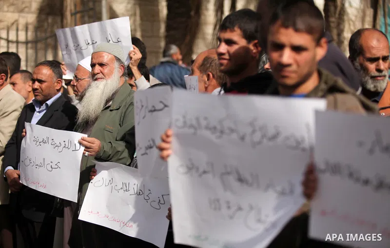 Palestinian workers hold banners during a protest demanding their rights in front of the Council of ministers headquarter, in Gaza city on November 24, 2016. Photo by Ashraf Amra