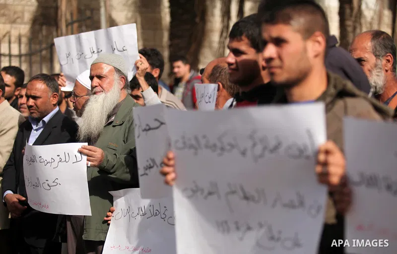 Palestinian workers hold banners during a protest demanding their rights in front of the Council of ministers headquarter, in Gaza city on November 24, 2016. Photo by Ashraf Amra