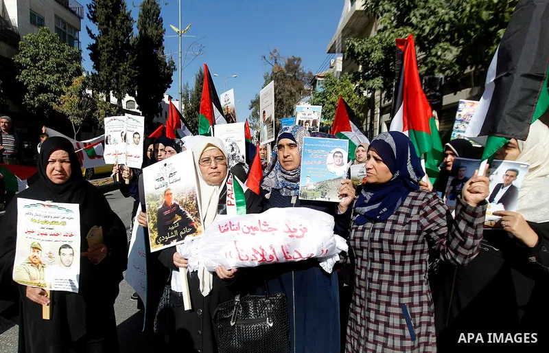 Palestinians hold banners during a protest demanding Israel return the bodies of Palestinians who allegedly stabbed Israelis, in the West Bank city of Hebron, on November 28, 2016. Photo by Wisam Hashlamoun