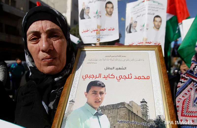 Palestinians hold banners during a protest demanding Israel return the bodies of Palestinians who allegedly stabbed Israelis, in the West Bank city of Hebron, on November 28, 2016. Photo by Wisam Hashlamoun
