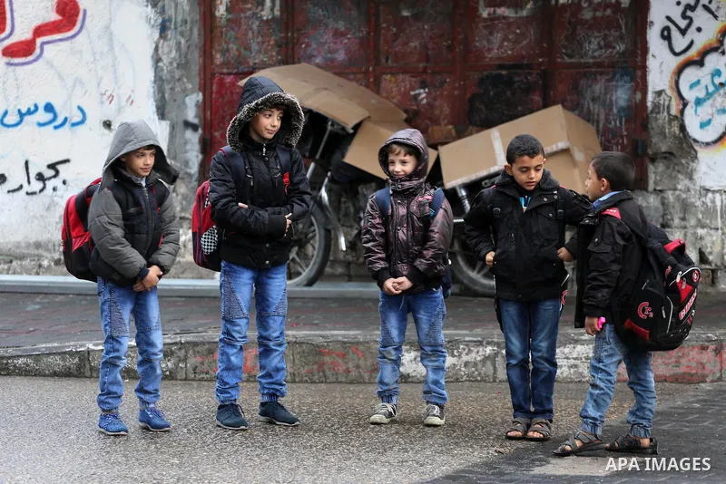 Palestinian school students walk at a street during rain and a cold spell at the al-Shati refugee camp in Gaza City on December 1, 2016. Photo by Mohammed Asad