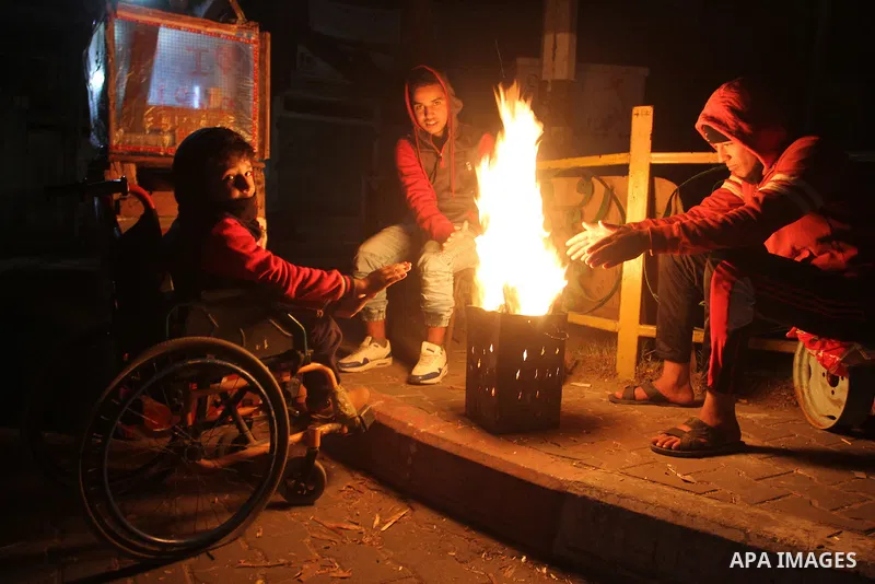 Palestinians warm themselves around a fire during the winter storm, in Rafah in the southern Gaza strip, on December 1, 2016. Photo by Abed Rahim Khatib