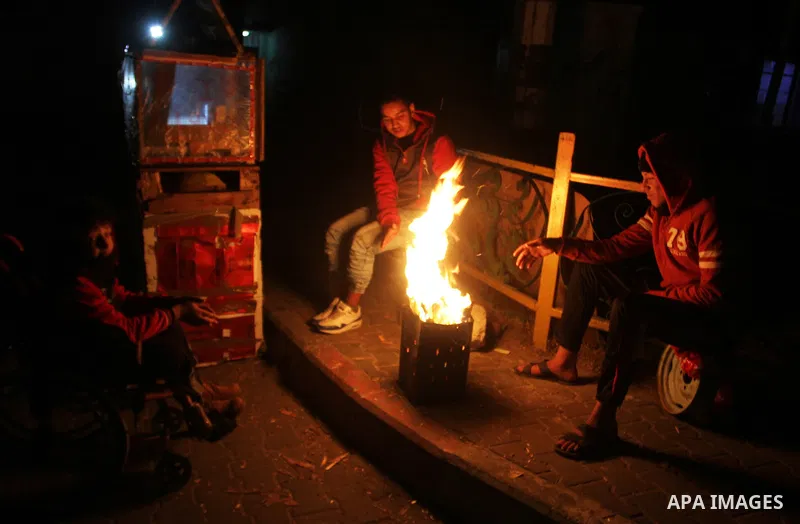 Palestinians warm themselves around a fire during the winter storm, in Rafah in the southern Gaza strip, on December 1, 2016. Photo by Abed Rahim Khatib