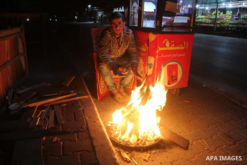 Palestinians warm themselves around a fire during the winter storm, in Rafah in the southern Gaza strip, on December 1, 2016. Photo by Abed Rahim Khatib