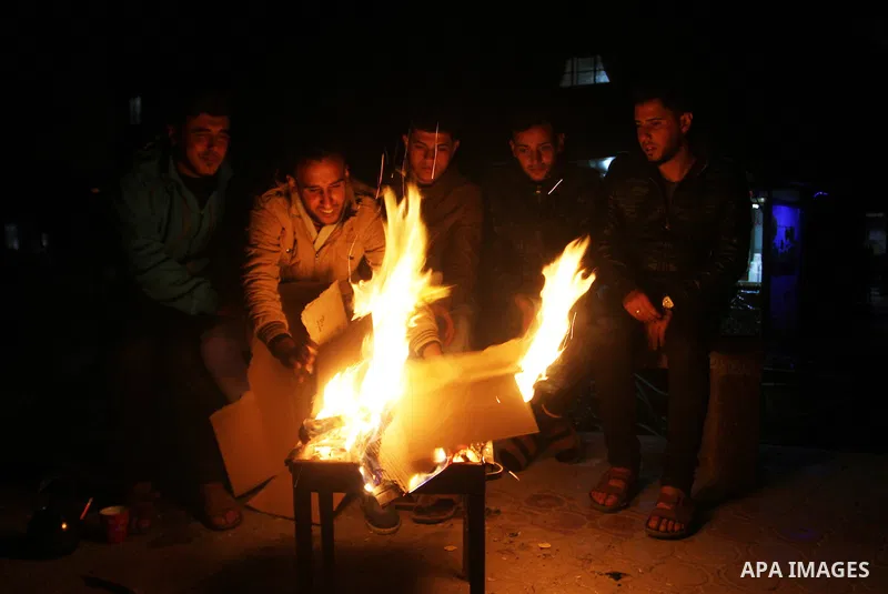Palestinians warm themselves around a fire during the winter storm, in Rafah in the southern Gaza strip, on December 1, 2016. Photo by Abed Rahim Khatib