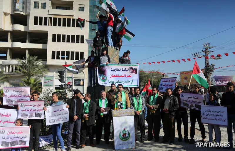 Palestinian youths hold banners and flags during a protest to show solidarity with the people in Burma and Syria, in Gaza city on December 6, 2016. Photo by Mohammed Asad