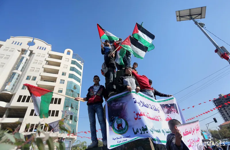 Palestinian youths hold banners and flags during a protest to show solidarity with the people in Burma and Syria, in Gaza city on December 6, 2016. Photo by Mohammed Asad