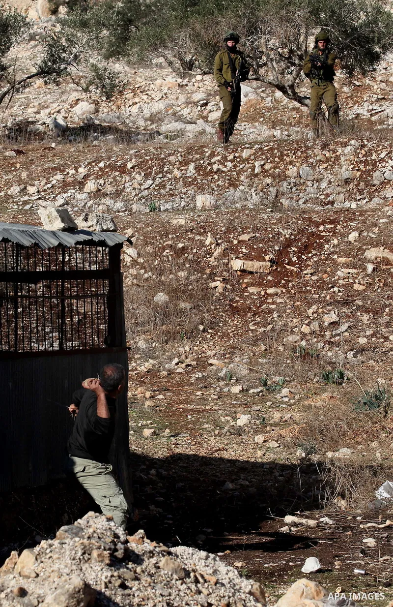 A Palestinian protester uses a slingshot to hurl stones towards Israeli security forces during clashes following a demonstration against the expropriation of Palestinian land by Israel in the village of Kfar Qaddum, near...