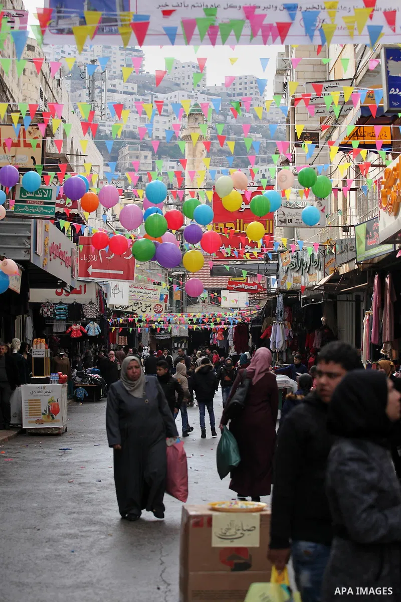 Palestinians walk at a market decorated during a ritual ceremony to commemorate the birth of the Prophet Mohammed, known in Arabic as "al-Mawlid al-Nabawi", in the West Bank city of Nablus on December 11, 2016. Photo by...