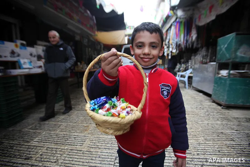 A Palestinian boy distributes a candy during a ritual ceremony to commemorate the birth of the Prophet Mohammed, known in Arabic as "al-Mawlid al-Nabawi", in the West Bank city of Nablus on December 11, 2016. Photo by Ne...