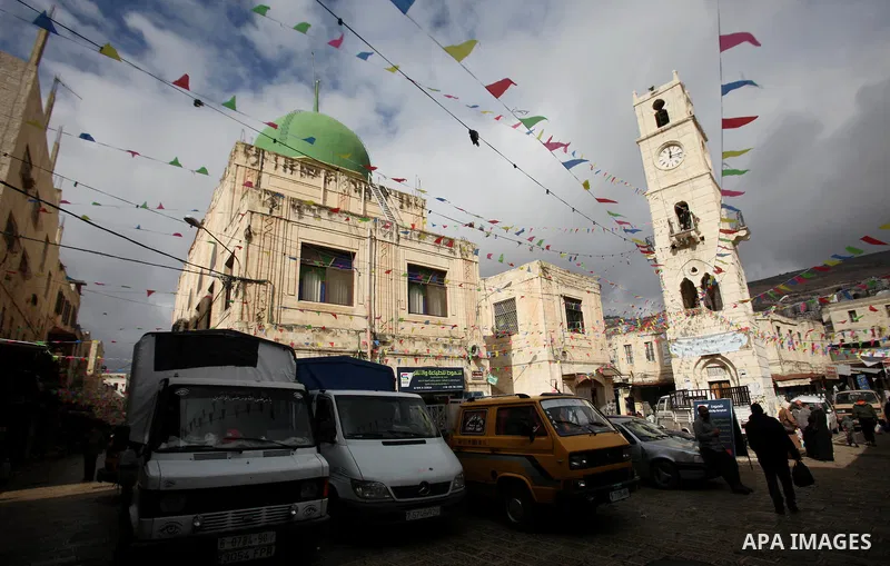 Palestinians walk at a market decorated during a ritual ceremony to commemorate the birth of the Prophet Mohammed, known in Arabic as "al-Mawlid al-Nabawi", in the West Bank city of Nablus on December 11, 2016. Photo by...