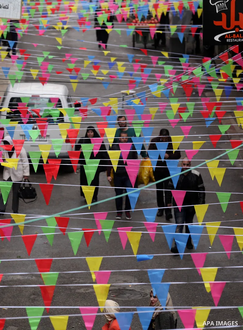 Palestinians walk at a market decorated during a ritual ceremony to commemorate the birth of the Prophet Mohammed, known in Arabic as "al-Mawlid al-Nabawi", in the West Bank city of Nablus on December 11, 2016. Photo by...