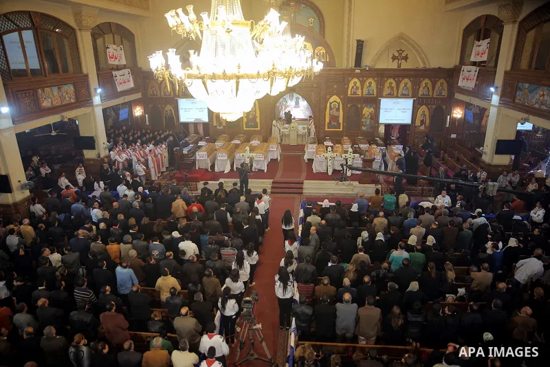 Egyptians stand next to the coffins of the victims of a bomb explosion that targeted a Coptic Orthodox Church the previous day in Cairo, during their funeral in the Egyptian capital's Nassr City neighbourhood on December...