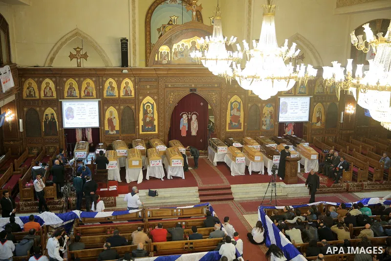 Egyptian clergymen stand next to the coffins of the victims of a bomb explosion that targeted a Coptic Orthodox Church the previous day in Cairo, during their funeral in the Egyptian capital's Nassr City neighbourhood on...