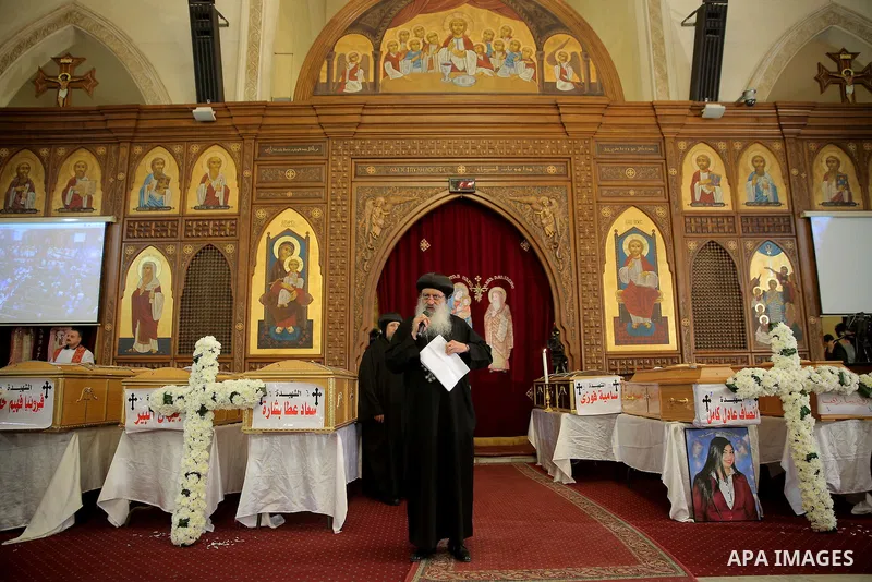 Egyptian clergymen stand next to the coffins of the victims of a bomb explosion that targeted a Coptic Orthodox Church the previous day in Cairo, during their funeral in the Egyptian capital's Nassr City neighbourhood on...