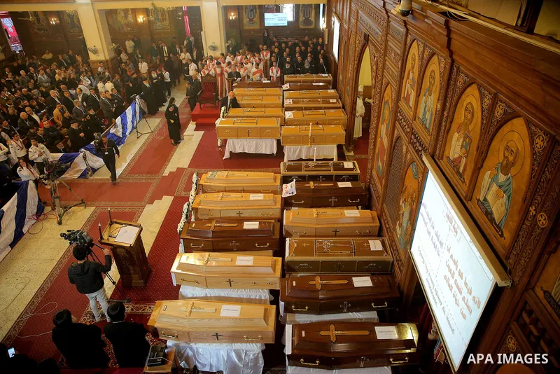 Egyptian clergymen stand next to the coffins of the victims of a bomb explosion that targeted a Coptic Orthodox Church the previous day in Cairo, during their funeral in the Egyptian capital's Nassr City neighbourhood on...