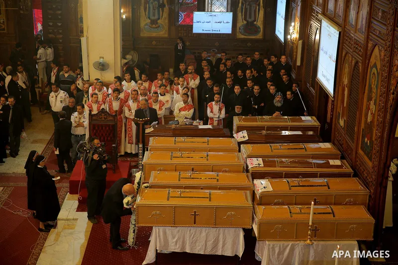 Egyptian clergymen stand next to the coffins of the victims of a bomb explosion that targeted a Coptic Orthodox Church the previous day in Cairo, during their funeral in the Egyptian capital's Nassr City neighbourhood on...