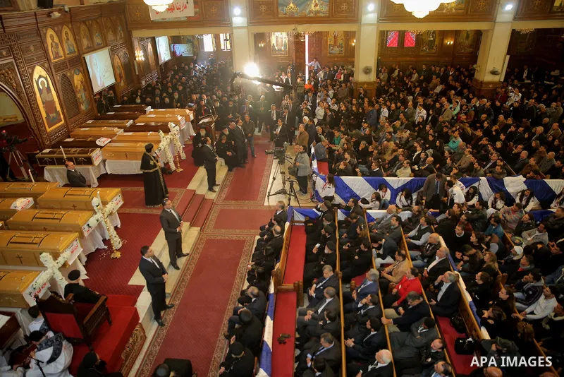 Egyptians stand next to the coffins of the victims of a bomb explosion that targeted a Coptic Orthodox Church the previous day in Cairo, during their funeral in the Egyptian capital's Nassr City neighbourhood on December...