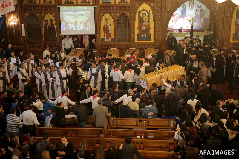 Egyptians stand next to the coffins of the victims of a bomb explosion that targeted a Coptic Orthodox Church the previous day in Cairo, during their funeral in the Egyptian capital's Nassr City neighbourhood on December...