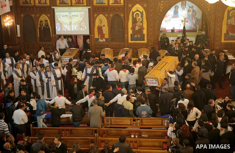 Egyptians stand next to the coffins of the victims of a bomb explosion that targeted a Coptic Orthodox Church the previous day in Cairo, during their funeral in the Egyptian capital's Nassr City neighbourhood on December...