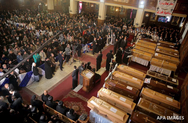 Egyptian clergymen stand next to the coffins of the victims of a bomb explosion that targeted a Coptic Orthodox Church the previous day in Cairo, during their funeral in the Egyptian capital's Nassr City neighbourhood on...