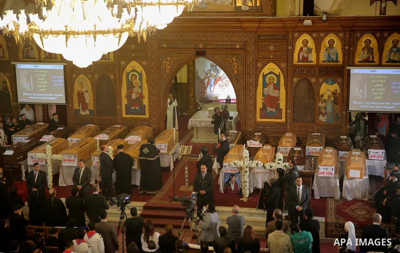 Egyptians stand next to the coffins of the victims of a bomb explosion that targeted a Coptic Orthodox Church the previous day in Cairo, during their funeral in the Egyptian capital's Nassr City neighbourhood on December...