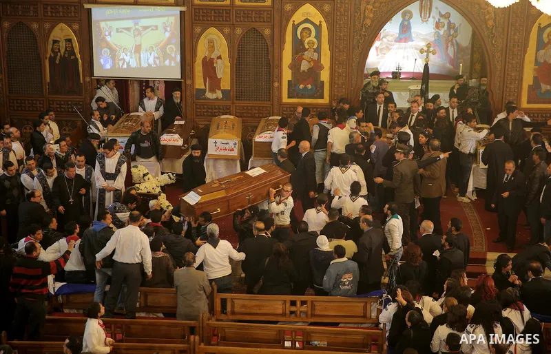Egyptians stand next to the coffins of the victims of a bomb explosion that targeted a Coptic Orthodox Church the previous day in Cairo, during their funeral in the Egyptian capital's Nassr City neighbourhood on December...