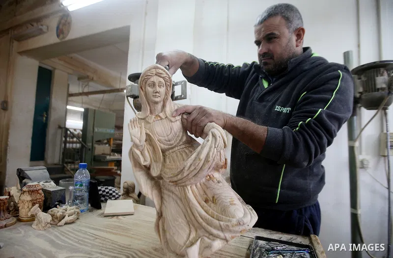 A Palestinian carpenter carves a wooden effigies of the the Holy Family at a workshop in the West Bank town of Bethlehem, on December 13, 2016. The traditional birthplace of Jesus Christ prepares to celebrate Christmas l...