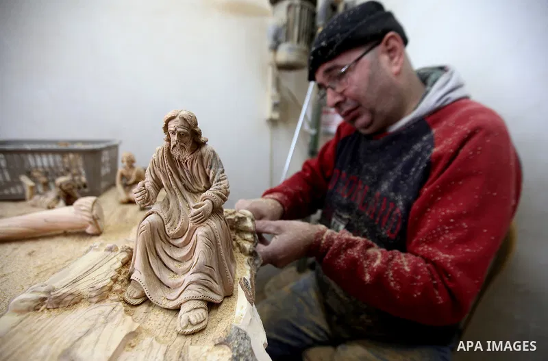 A Palestinian carpenter carves a wooden effigies of the the Holy Family at a workshop in the West Bank town of Bethlehem, on December 13, 2016. The traditional birthplace of Jesus Christ prepares to celebrate Christmas l...