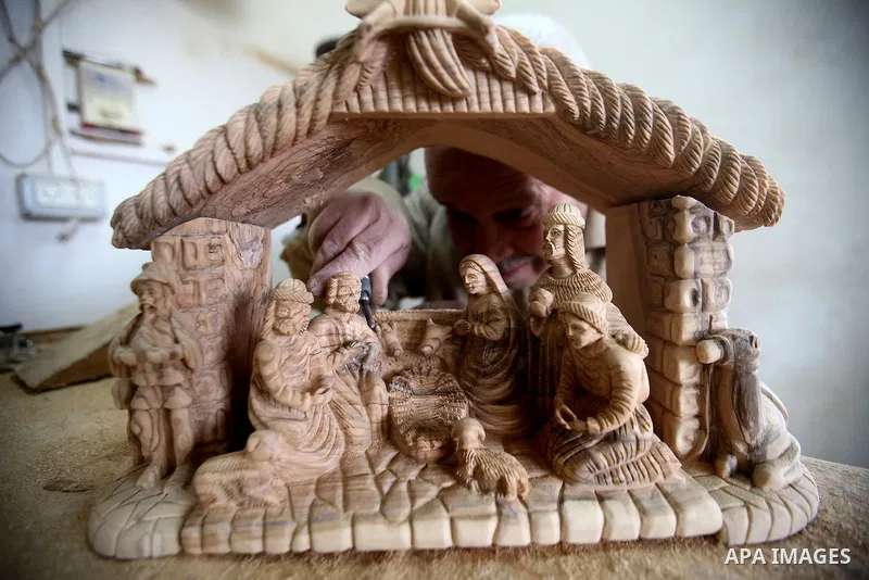 A Palestinian carpenter carves a wooden effigies of the the Holy Family at a workshop in the West Bank town of Bethlehem, on December 13, 2016. The traditional birthplace of Jesus Christ prepares to celebrate Christmas l...