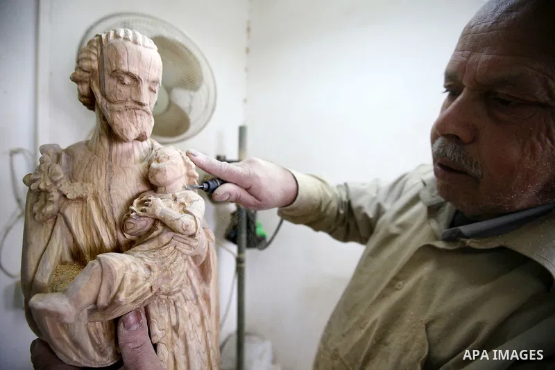 A Palestinian carpenter carves a wooden effigies of the the Holy Family at a workshop in the West Bank town of Bethlehem, on December 13, 2016. The traditional birthplace of Jesus Christ prepares to celebrate Christmas l...