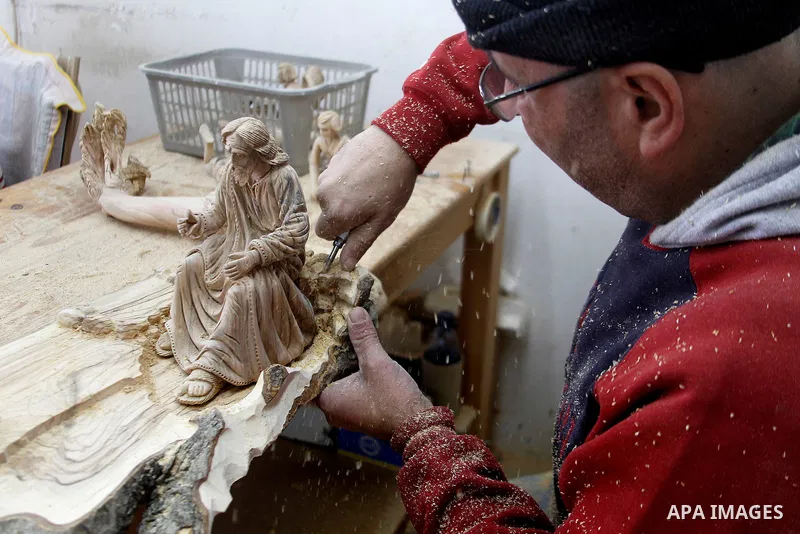 A Palestinian carpenter carves a wooden effigies of the the Holy Family at a workshop in the West Bank town of Bethlehem, on December 13, 2016. The traditional birthplace of Jesus Christ prepares to celebrate Christmas l...