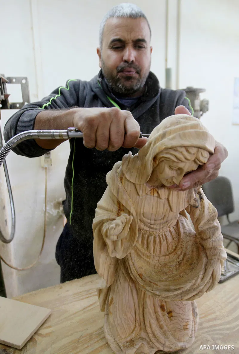 A Palestinian carpenter carves a wooden effigies of the the Holy Family at a workshop in the West Bank town of Bethlehem, on December 13, 2016. The traditional birthplace of Jesus Christ prepares to celebrate Christmas l...