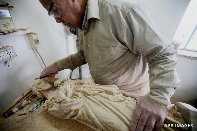 A Palestinian carpenter carves a wooden effigies of the the Holy Family at a workshop in the West Bank town of Bethlehem, on December 13, 2016. The traditional birthplace of Jesus Christ prepares to celebrate Christmas l...