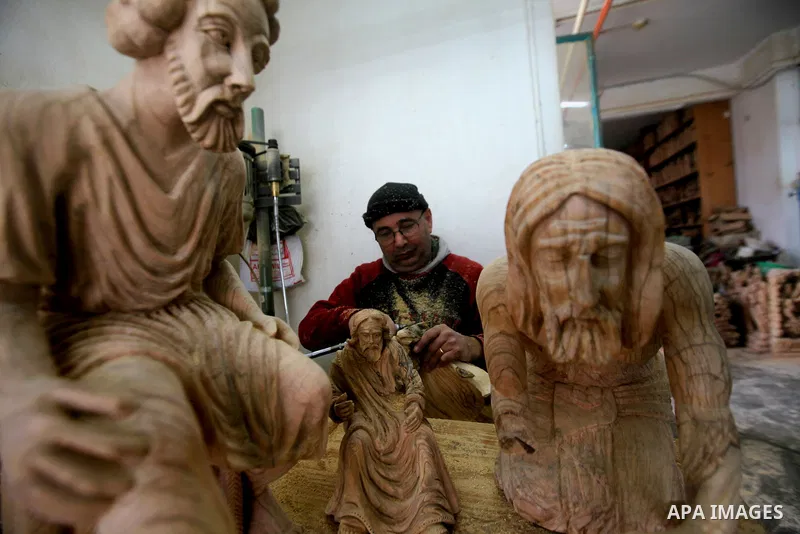 A Palestinian carpenter carves a wooden effigies of the the Holy Family at a workshop in the West Bank town of Bethlehem, on December 13, 2016. The traditional birthplace of Jesus Christ prepares to celebrate Christmas l...