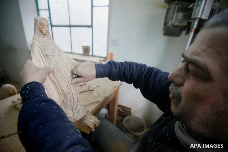 A Palestinian carpenter carves a wooden effigies of the the Holy Family at a workshop in the West Bank town of Bethlehem, on December 13, 2016. The traditional birthplace of Jesus Christ prepares to celebrate Christmas l...